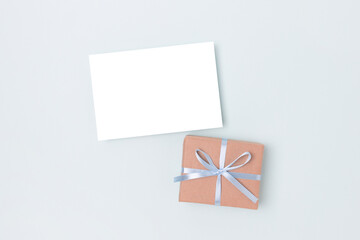 Paper sheet mockup and present tied with a ribbon on a blue  background. Gift box and greeting card template.