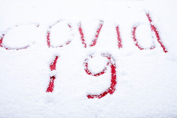 covid -19 written with a finger in the snow on the hood of a red car, lockdown, virus mutation