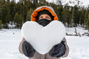 Fototapeta na wymiar Snow heart in woman’s hand on the background of mountains.