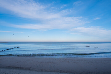 calm blue baltic sea against a blue sky with white cirrus clouds and an empty sandy beach, the city of Pionersky, Kaliningrad region