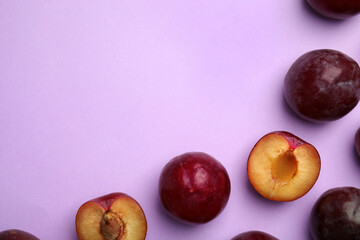 Delicious ripe plums on violet background, flat lay. Space for text