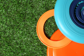 Plastic frisbee disks and ring on green grass, flat lay. Space for text