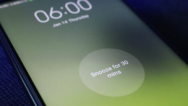 The alarm clock on the phone rings at 6 am, finger taps the button - Snooze the alarm for 30 minutes.