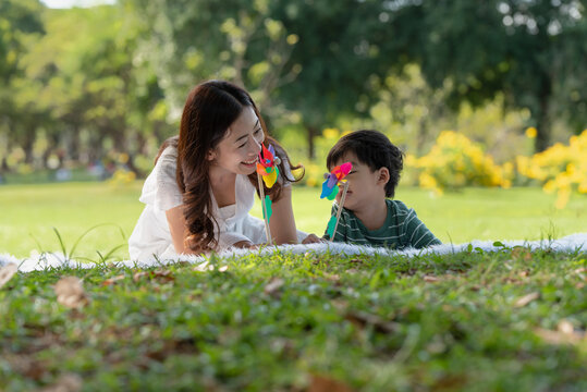 Asian Family Having Fun Mother And Her Son Playing Windmill In The Garden Together