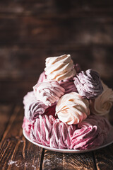 Appetizing multi-colored zephyr on a plate on a wooden table. Tea drinking concept. Confectionery decoration. Place for text