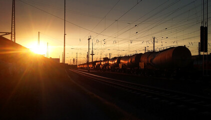 Freight train transporting goods on railroad towards glowing rusty evening sky. Powering industry and economy in a world of globalisation.