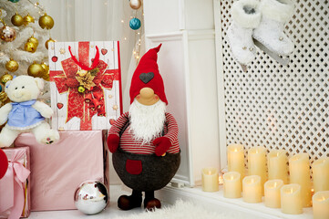 Christmas gnome with gifts by the fireplace under the Christmas tree