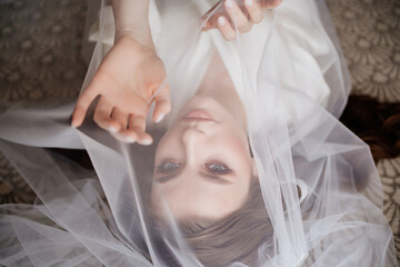 view top. a beautiful young woman in robe is lying under a veil.