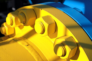 Two blue and yellow gas pipes are connected by large bolts and nuts. Background for suppliers of...