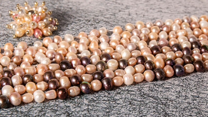 Iridescent natural white, creamy and black  pearl necklaces close up on a gray surface. Luxurious...
