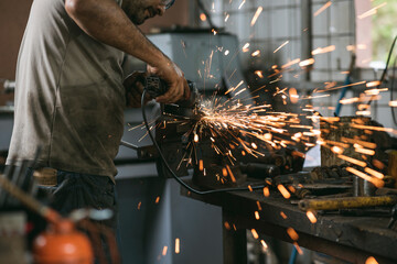 Hombre con gorra trabajando en un taller de mecánica y precisión en un torno 