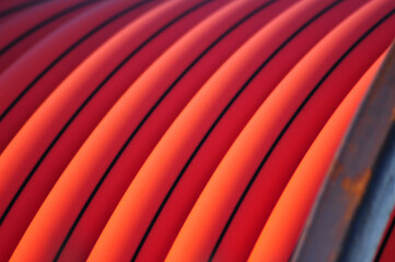 Detail of coiled orange conduit with black tracer lines, commonly used for underground fiber-optic...