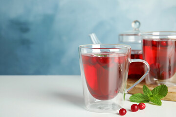 Tasty hot cranberry tea with mint and fresh berries on light table. Space for text