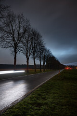 A country road with a car moving towards camera at night