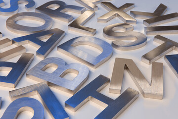 Shiny letters milled from metal lying on table.