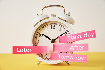 Procrastination, delay and postpone concept. Alarm clock with sticky notes   later, tomorrow, next...