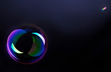 Pompa de jabón. Gran pompa de jabón con fondo oscuro. Fragilidad y ligereza.