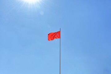 Red Turkish flag waving in the wind with selective focus on blue sky background with sunlight. National symbol of Turkey. 