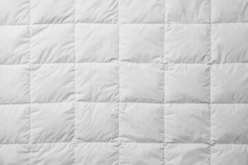 Soft quilted blanket as background, top view