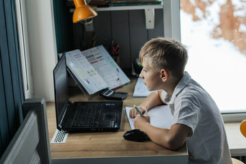 Fototapeta na wymiar A boy learns lessons at home distance learning on a laptop