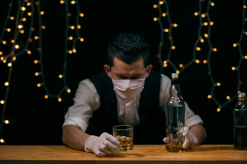 Barman pouring whiskey wearing  protective mask on the bar counter 