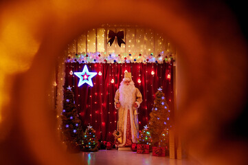 Santa Claus among gifts on the background of Christmas lights