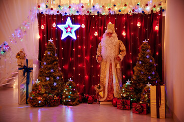 Santa Claus among gifts on the background of Christmas lights
