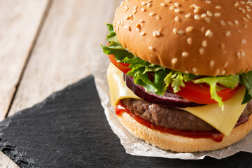 Cheeseburger with beef,tomato, lettuce and onion on wooden table