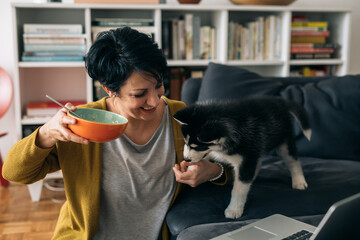 woman sitting on sofa with her dog and having snack