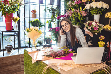 Women florist looking laptop got order at counter of her flower shop, occupation working concept....