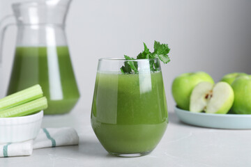 Glass of fresh celery juice on light marble table
