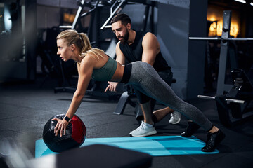 Young woman doing exercises while using the ball in the gym