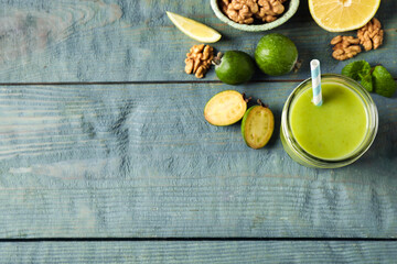 Fresh feijoa smoothie and fresh ingredients on wooden table, flat lay. Space for text