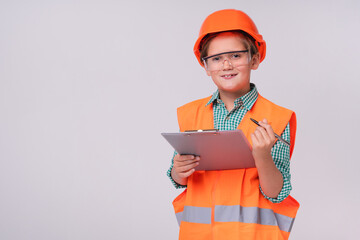 Cute small kid in uniform and hardhat of construction worker with clipboard isolated over grey background