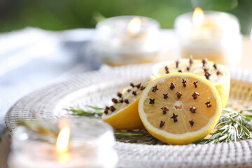 Lemons with cloves and fresh rosemary on plate outdoors, closeup. Natural homemade repellent