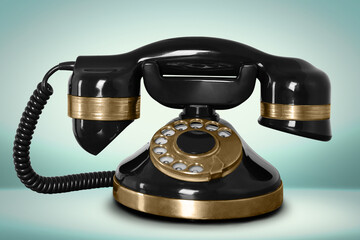 Vintage black corded telephone on pale turquoise background