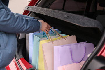 Woman putting shopping bags in car outdoors, closeup
