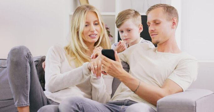 Beautiful young parents and their cute little son are using a digital tablet and smiling while spending time together.