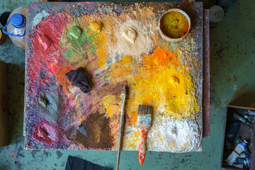 Wooden art palette with color paints and a brushes, top view