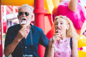 senior old couple celebration for Valentine's Day at Amusement theme park enjoying freedom relaxing, grandmother and grandfather smiling and fun, time to date and married