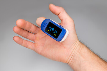 A pulse oximeter on the finger of a man's hand measures the amount of oxygen in the blood and the pulse.