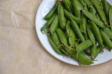 Green pea pods from farmland. Pea freshly picked. Organic spring pea pods. Vintage paper background. Fresh vegetables. Healthy eating. Country garden harvest.
