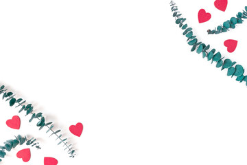 Red wooden figures in the shape of a heart and eucalyptus branches are on a white background. Composition for Valentine's Day. Flat lay. Top view. Copy space.