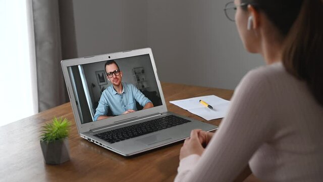 Online interview concept. Side view a female is has online video meeting with a pleasant young man on a laptop screen. A confident woman is talking, an applicant is listening and nods