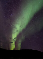 Aurora in the night sky in Norway with an Orionid shooting star
