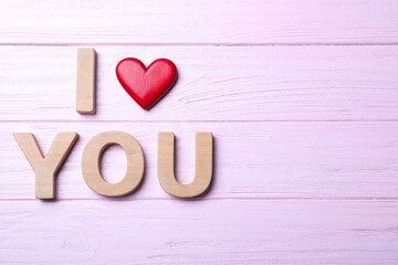 Phrase I Love You made of decorative heart and letters on pink wooden background, flat lay. Space for text