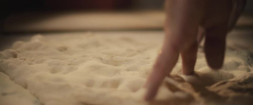 Chef preparing traditional pizza al taglio dough with his hands, slowly kneading dough.