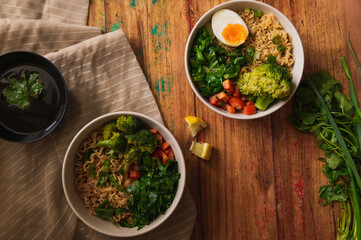 Veggie bowls of noodles on top of fabric and wooden table. Flat design.
