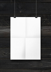 White folded poster hanging on a concrete wall with clips