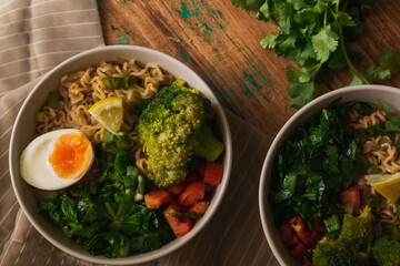 Veggie bowls of noodles on top of fabric and wooden table. Flat design.
